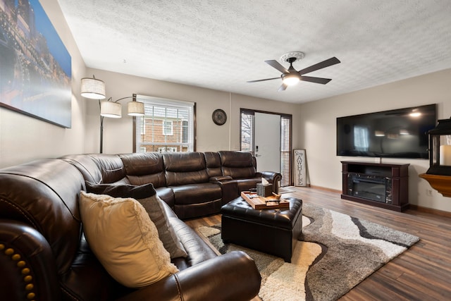 living room with ceiling fan, wood-type flooring, and a textured ceiling