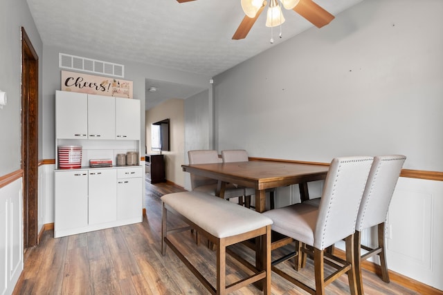 dining area featuring hardwood / wood-style flooring, ceiling fan, and a textured ceiling