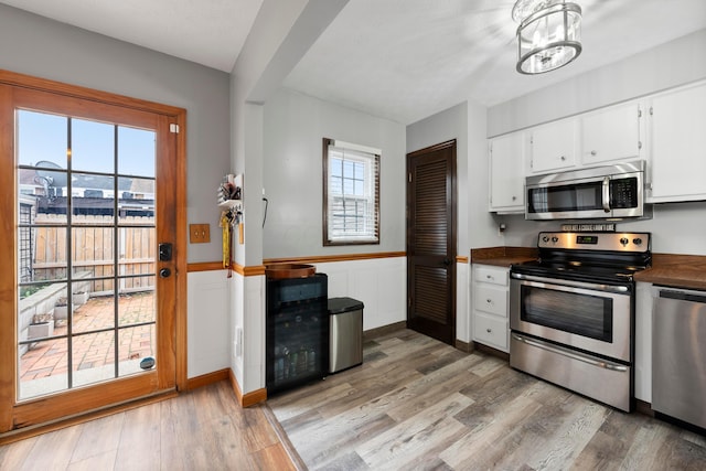 kitchen featuring a wealth of natural light, white cabinetry, light wood-type flooring, and appliances with stainless steel finishes