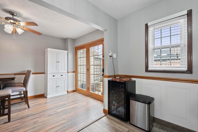 home office featuring light hardwood / wood-style floors, a textured ceiling, wine cooler, and french doors