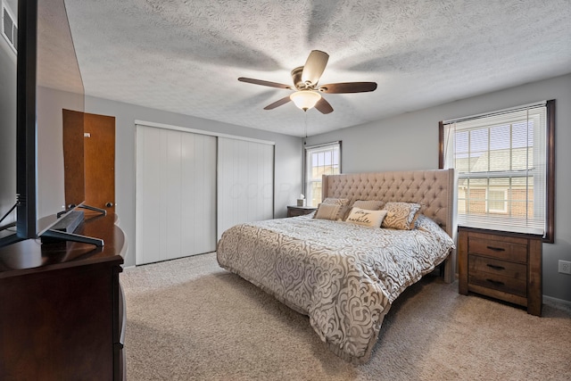 carpeted bedroom with ceiling fan, a textured ceiling, and multiple windows