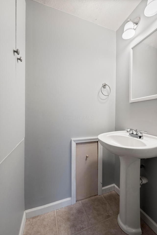 bathroom featuring a textured ceiling, tile patterned floors, and sink