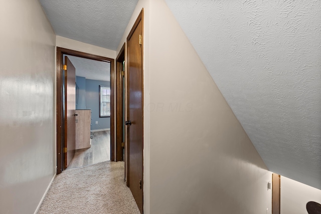 hall featuring light colored carpet and a textured ceiling