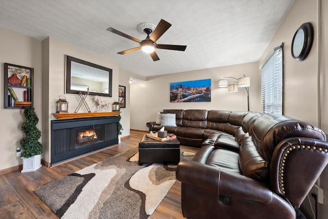 living room with a textured ceiling, ceiling fan, and dark hardwood / wood-style floors