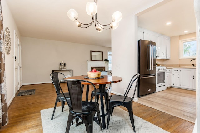 dining room with sink, an inviting chandelier, and light wood-type flooring