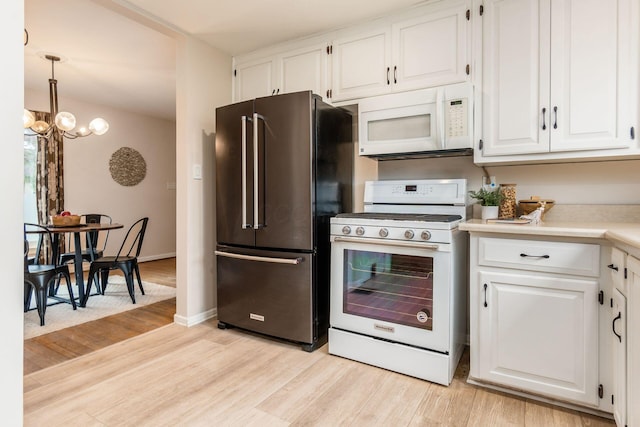 kitchen with white appliances, white cabinets, light hardwood / wood-style flooring, decorative light fixtures, and a chandelier