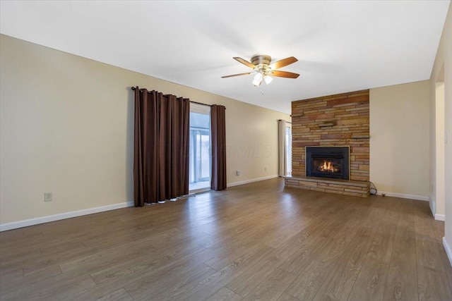 unfurnished living room featuring ceiling fan, a stone fireplace, and wood-type flooring