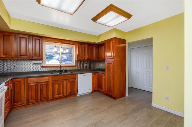 kitchen with light wood-type flooring, white appliances, backsplash, and sink