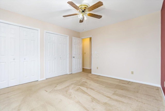 unfurnished bedroom with carpet, two closets, and ceiling fan