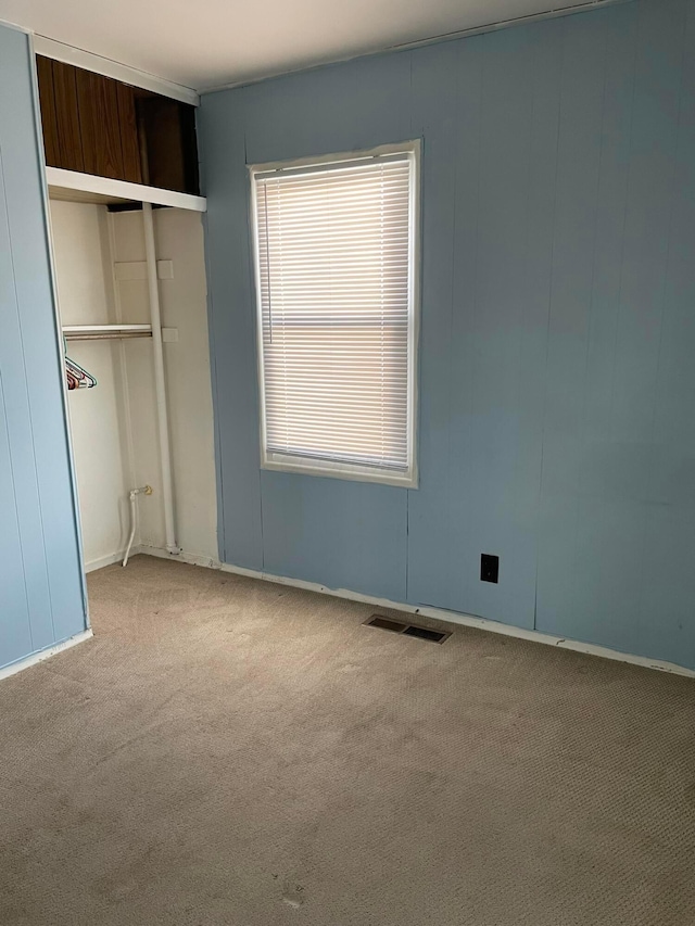 unfurnished bedroom with light carpet and a closet