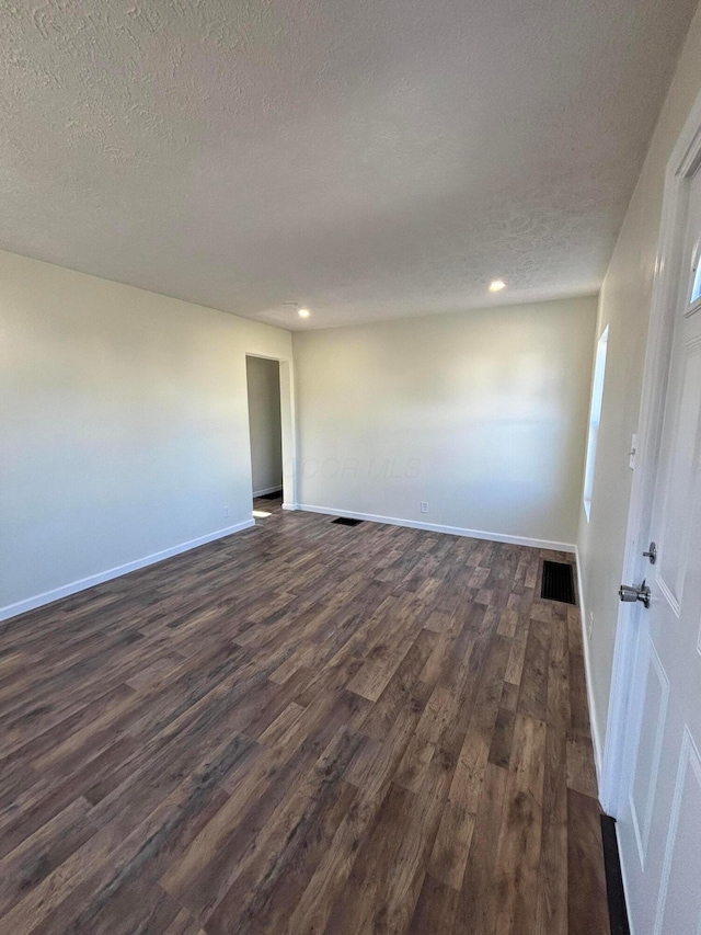 spare room featuring dark hardwood / wood-style flooring and a textured ceiling