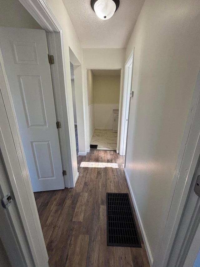 hall with dark wood-type flooring and a textured ceiling