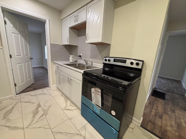 kitchen with tasteful backsplash, white cabinetry, sink, and electric range