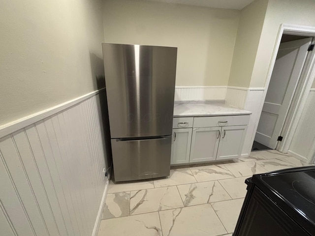 kitchen with stainless steel refrigerator, white cabinetry, and black range with electric stovetop