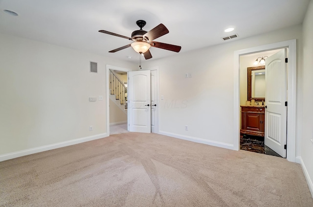 unfurnished bedroom with dark colored carpet, connected bathroom, and ceiling fan