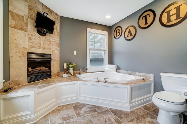 bathroom with toilet, a bath, and a tile fireplace