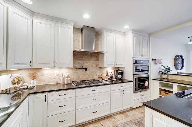 kitchen with white cabinets, decorative backsplash, wall chimney exhaust hood, and appliances with stainless steel finishes