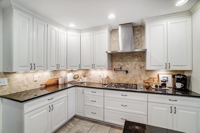 kitchen with backsplash, white cabinetry, stainless steel gas stovetop, and wall chimney range hood