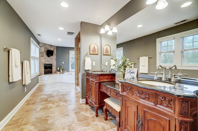 bathroom with a tile fireplace, a chandelier, vanity, and independent shower and bath