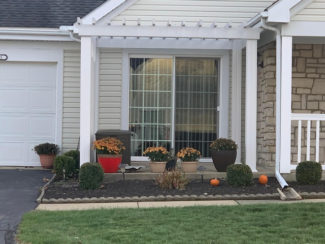 property entrance with a pergola and a garage