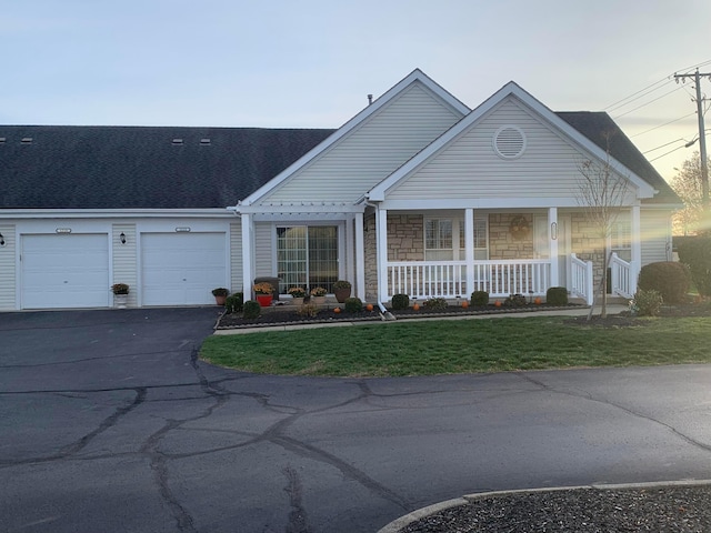 view of front of home featuring a yard, covered porch, and a garage