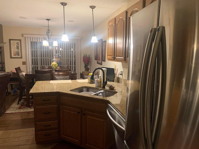 kitchen with appliances with stainless steel finishes, sink, decorative light fixtures, a notable chandelier, and dark hardwood / wood-style floors