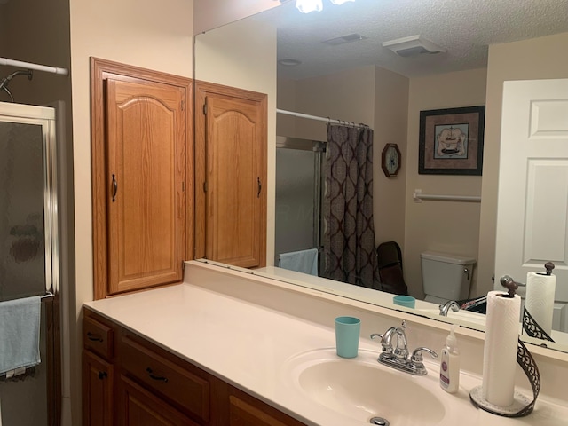 bathroom with a shower with shower curtain, vanity, toilet, and a textured ceiling