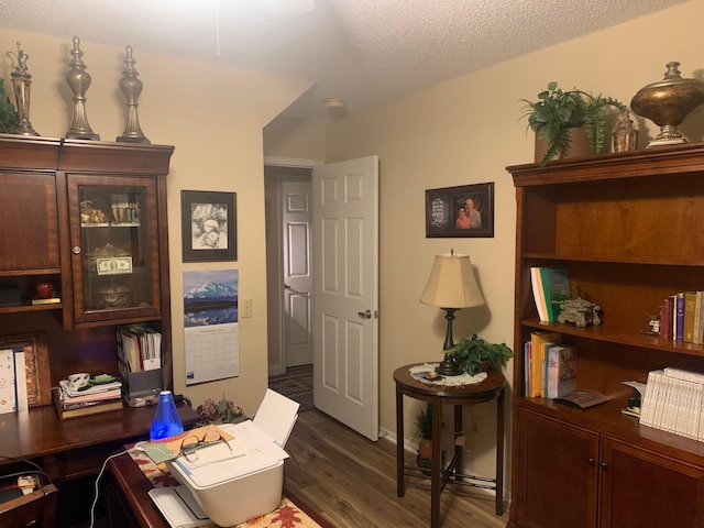 home office with dark hardwood / wood-style flooring and a textured ceiling