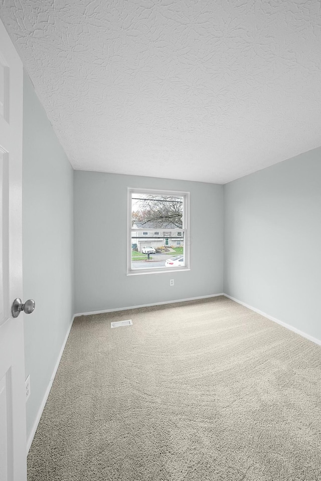 carpeted spare room with a textured ceiling