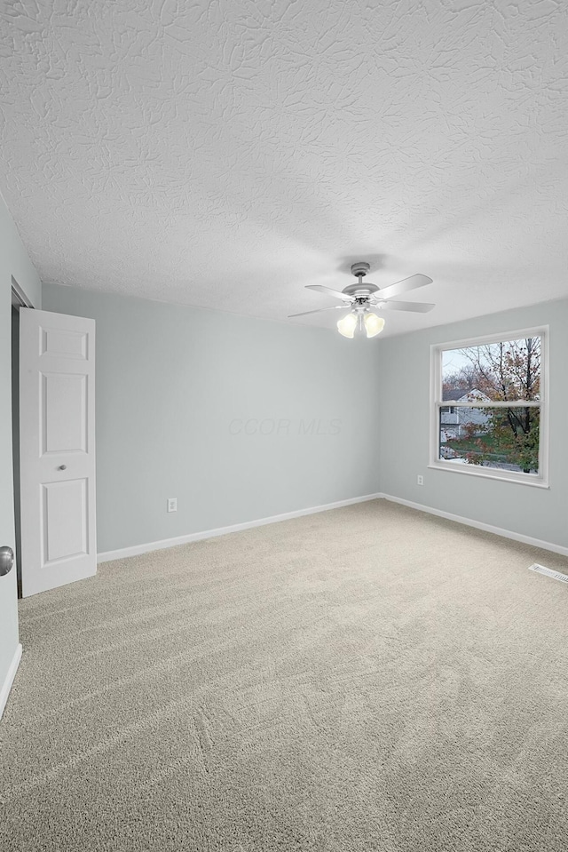 unfurnished room with carpet, ceiling fan, and a textured ceiling