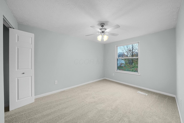 unfurnished room with ceiling fan, carpet floors, and a textured ceiling