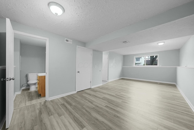 basement with a textured ceiling and light hardwood / wood-style flooring