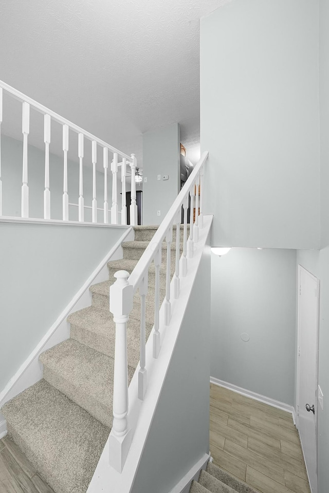 staircase featuring wood-type flooring and a textured ceiling