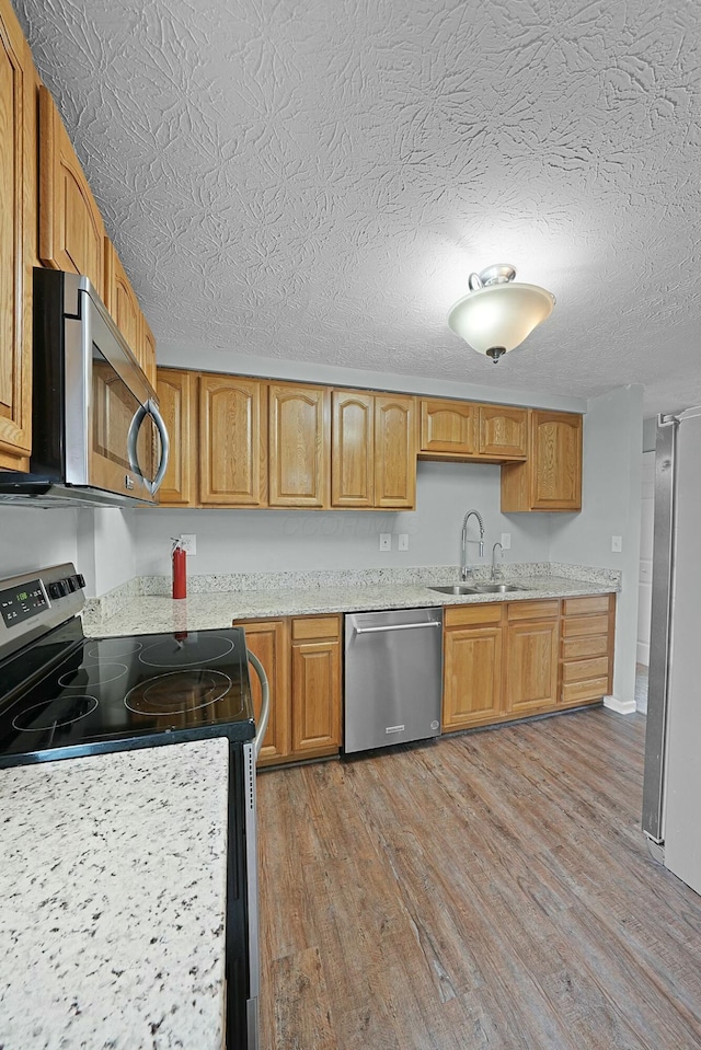 kitchen featuring a textured ceiling, sink, stainless steel appliances, and light hardwood / wood-style flooring