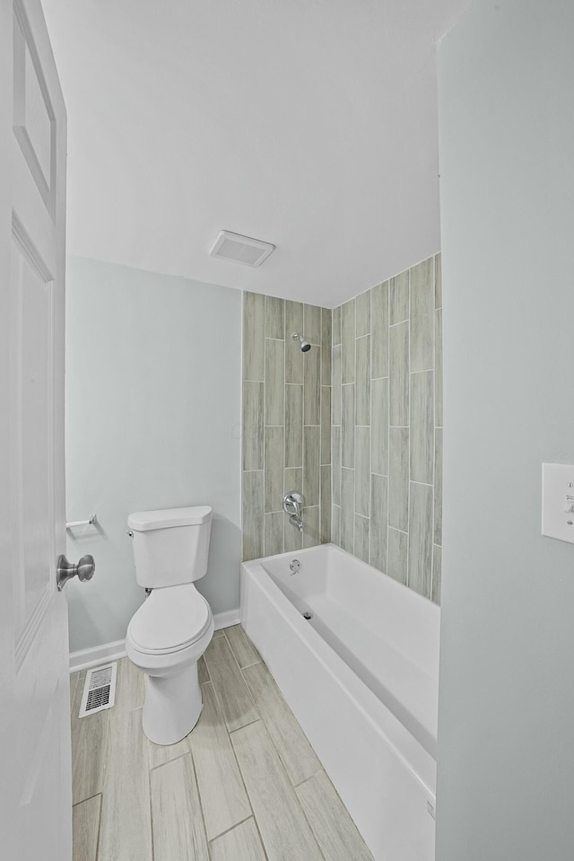 bathroom featuring toilet and tiled shower / bath