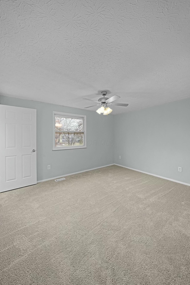 carpeted empty room featuring ceiling fan and a textured ceiling