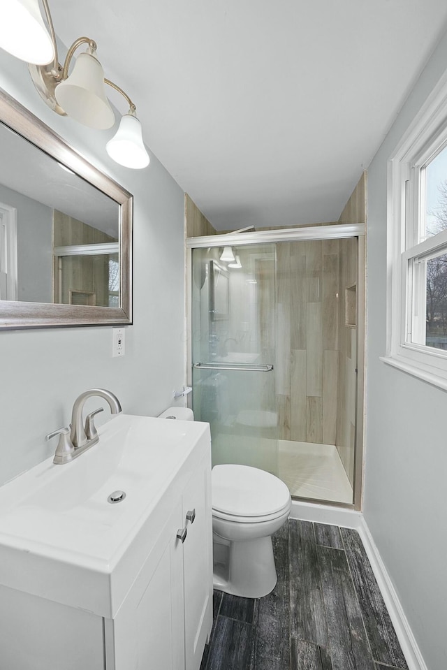 bathroom featuring vanity, toilet, wood-type flooring, and a shower with door