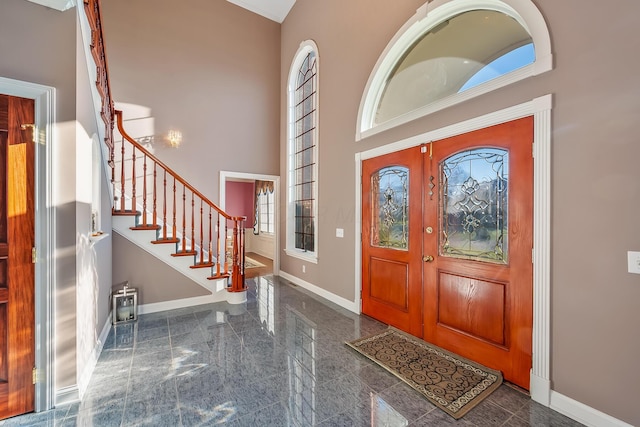 entrance foyer featuring a towering ceiling, ornamental molding, and french doors