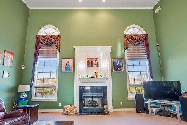 living room with a fireplace, carpet, crown molding, and a high ceiling