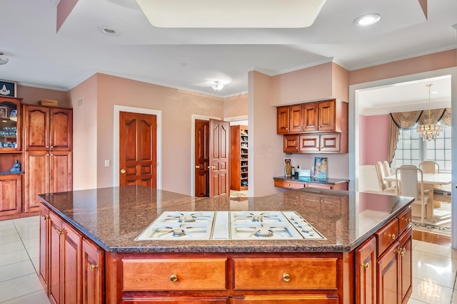 kitchen featuring white gas stovetop, crown molding, pendant lighting, a chandelier, and a kitchen island