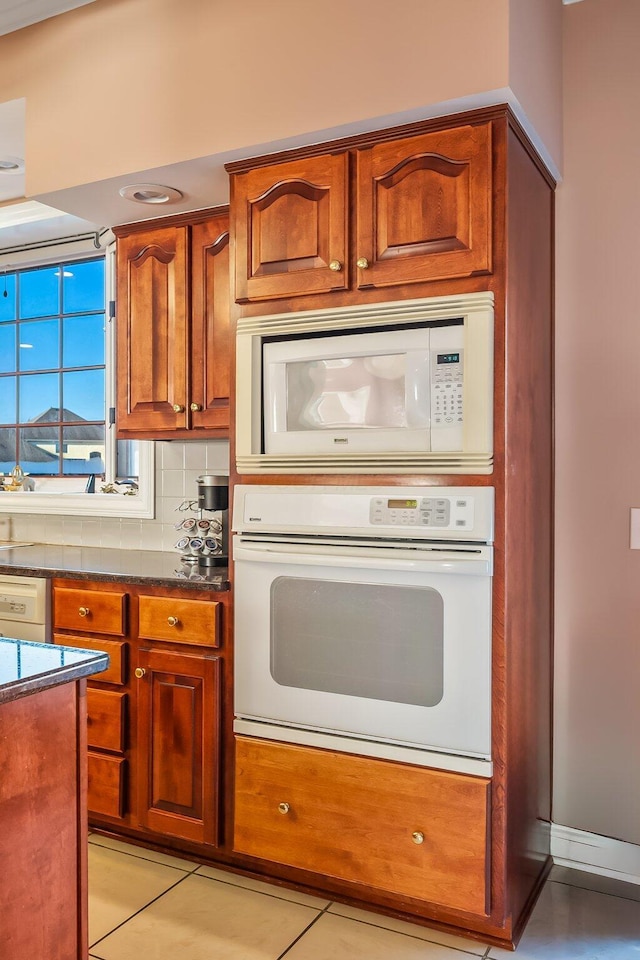 kitchen with white appliances, backsplash, and light tile patterned flooring