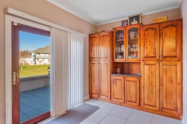 doorway with light tile patterned floors and crown molding