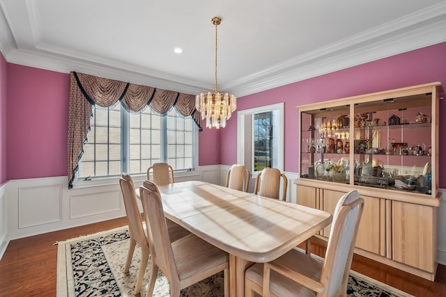 dining area with plenty of natural light, dark wood-type flooring, a notable chandelier, and ornamental molding