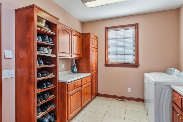 laundry room with washing machine and dryer, light tile patterned flooring, and cabinets