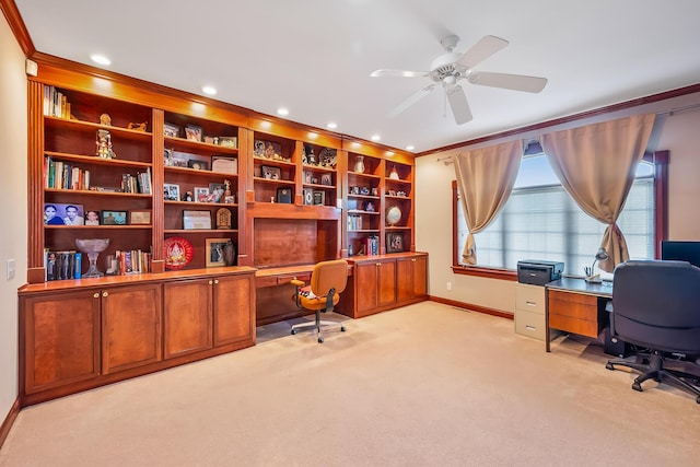 carpeted home office featuring ceiling fan, built in desk, and crown molding