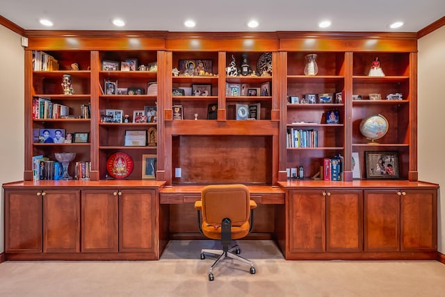 carpeted office space with built in desk and crown molding