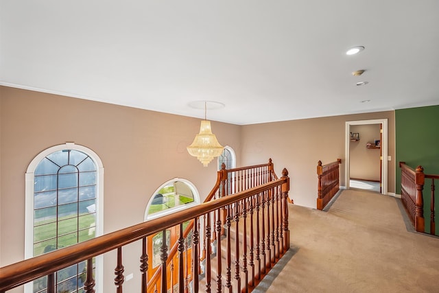 hallway featuring a notable chandelier and light carpet