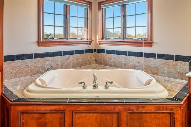 bathroom featuring a wealth of natural light and tiled bath