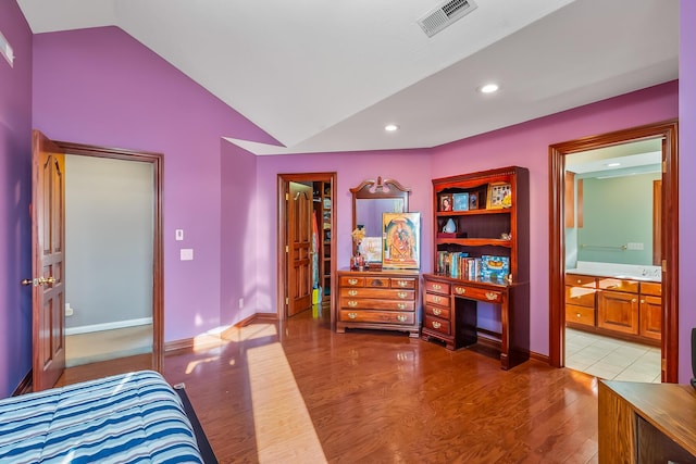 bedroom with vaulted ceiling, light hardwood / wood-style flooring, and ensuite bath