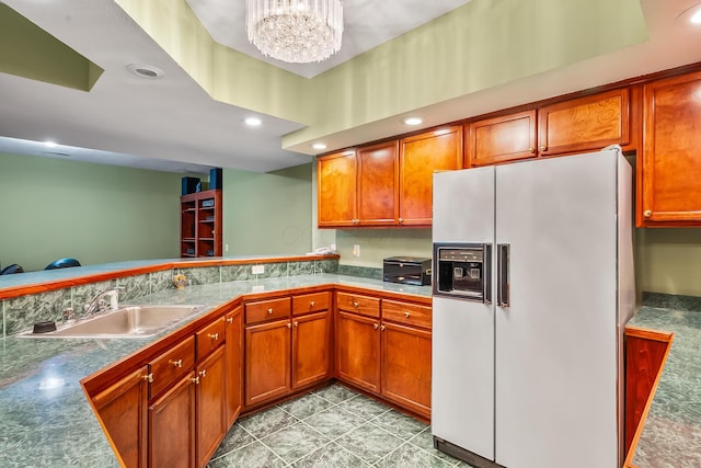 kitchen featuring light tile patterned flooring, white refrigerator with ice dispenser, sink, and an inviting chandelier